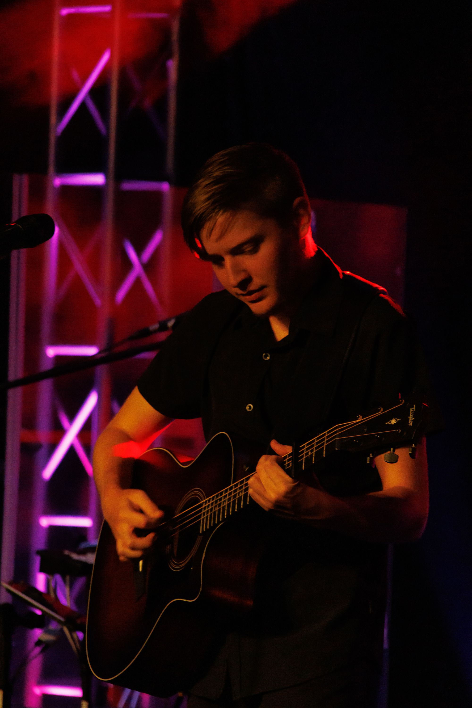 Trevor playing guitar in red stage light